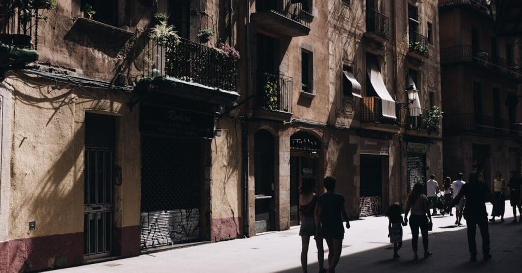 A bustling urban street in Barcelona with historical architecture and shadow play on the facades.