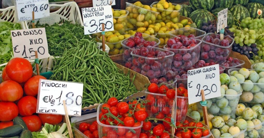 Vibrant fruit and vegetable display at an outdoor market stall showcasing fresh produce.