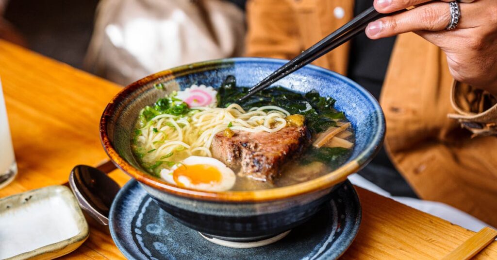 A vibrant bowl of ramen with chopsticks, showcasing a perfect mix of ingredients.