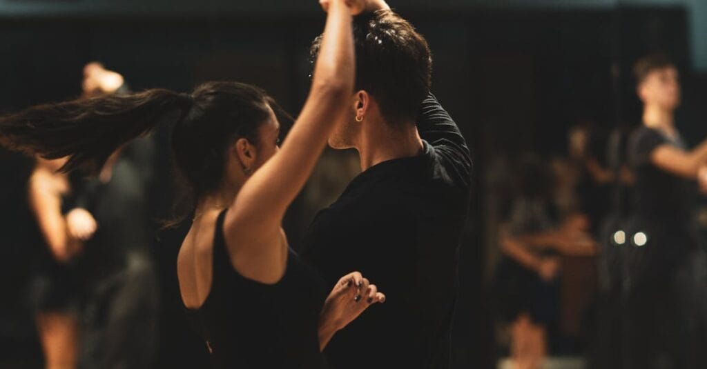 A couple elegantly performing tango inside a dance studio with onlookers.