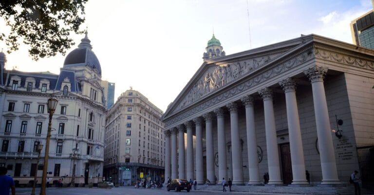 View of a neoclassical building in Buenos Aires with grand columns and urban scene.