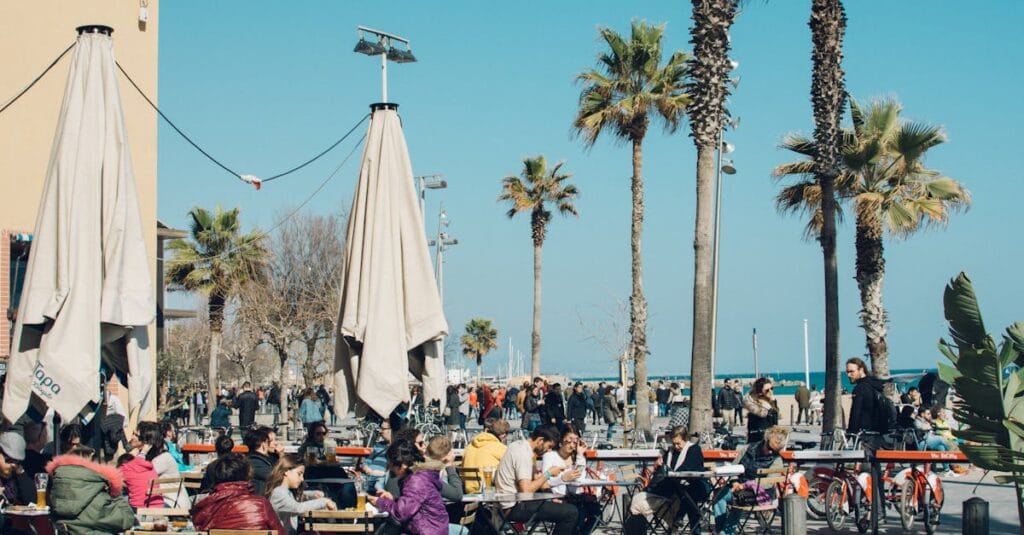 Colorful outdoor cafe in Barcelona with people enjoying a sunny day by the beach.