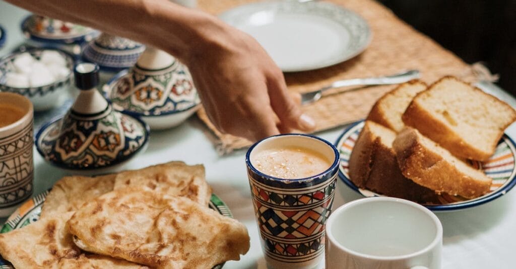 Enjoy a Moroccan breakfast setup with mint tea, crepes, and bread in a traditional setting.
