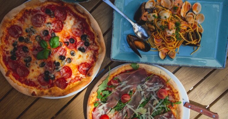 Top view of delicious pizzas and seafood pasta, perfect for Italian food enthusiasts. Captured in natural light.