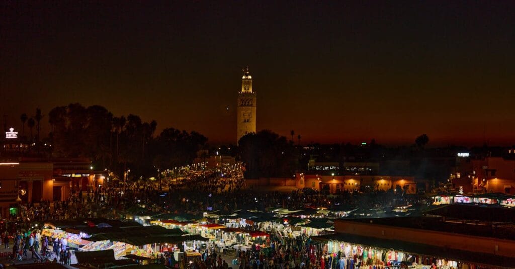 Experience the bustling night market in Marrakesh, Morocco, illuminated against a stunning twilight sky.