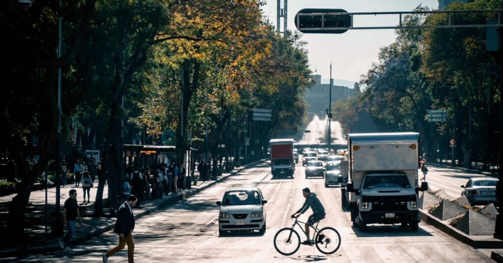 Busy city street in Mexico City featuring cyclists, pedestrians, and traffic under clear skies.