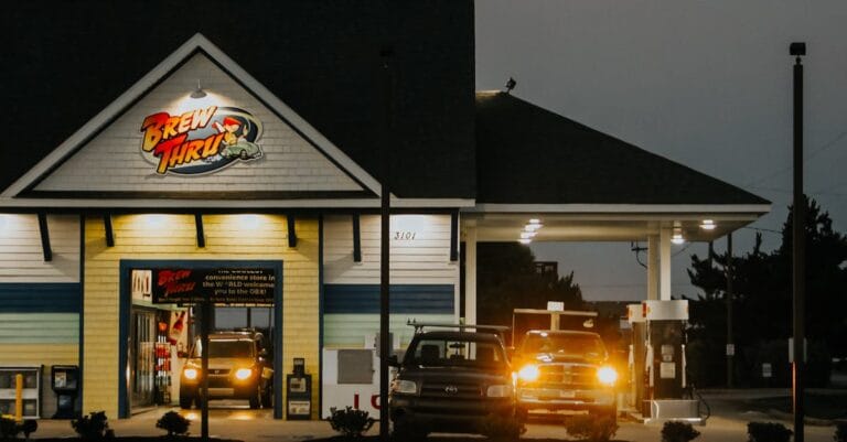 Illuminated drive-thru restaurant at night with cars lined up, showcasing a modern exterior.