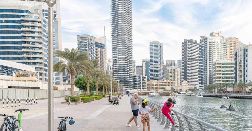 A family enjoys a walk on the Dubai Marina promenade with skyline and water views.