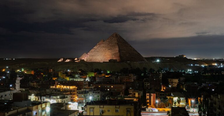 A stunning night view of the Giza Pyramids illuminated, capturing the vibrant cityscape of Giza, Egypt.