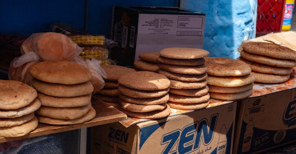 Stack of traditional Moroccan khobz bread displayed at an outdoor market stand.