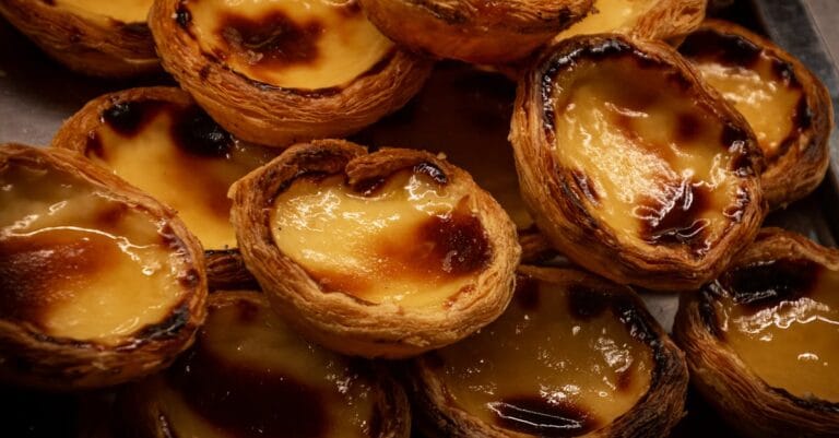 A tempting display of traditional Portuguese Pastel de Nata pastries, glistening with caramelized tops.