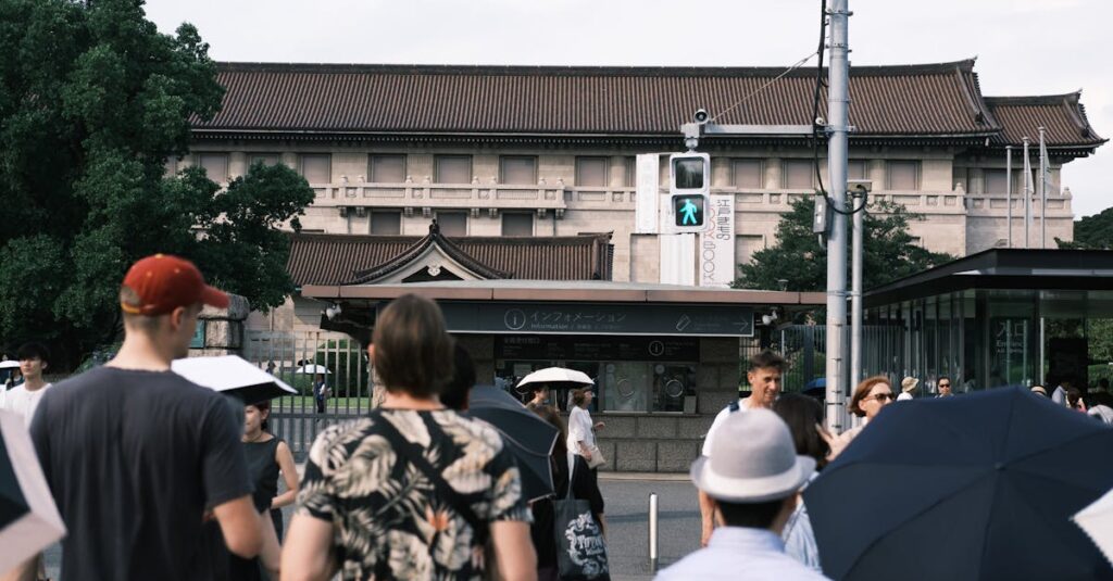 A lively urban scene featuring people crossing in front of a historical building on a cloudy day.