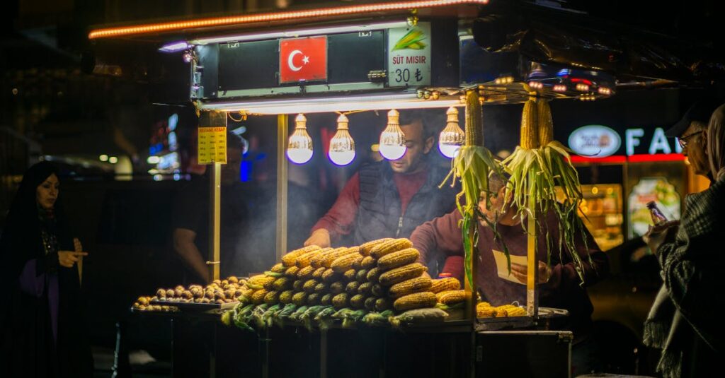 Vibrant outdoor Turkish street market stall featuring grilled corn cobs, bustling with people at night.