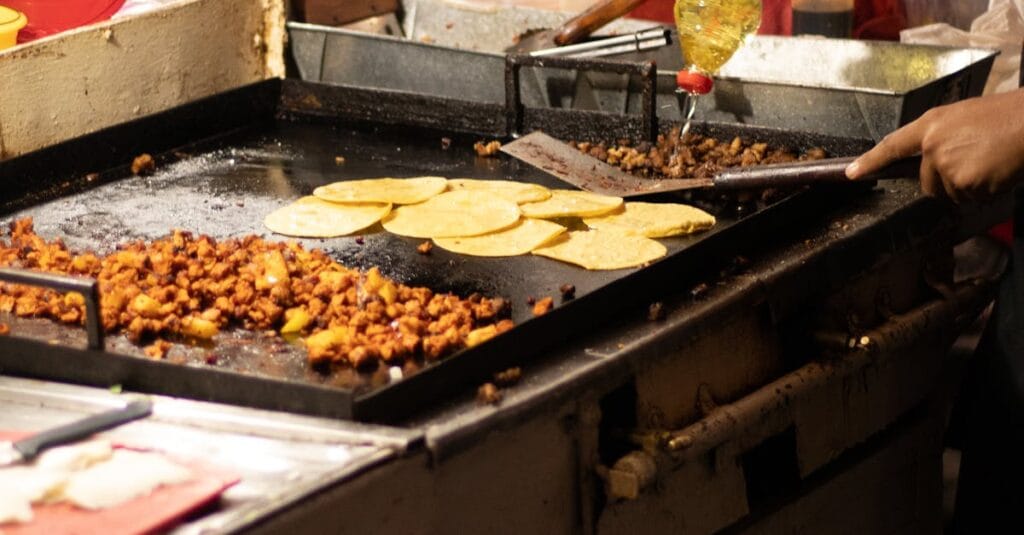 Men cooking authentic Mexican tacos at a street food stand in Mexico City.
