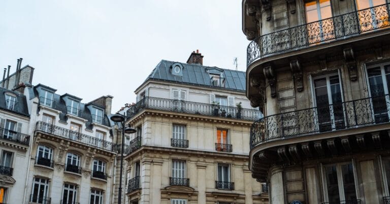 Classic Parisian buildings with intricate balconies at dusk, showcasing European charm.
