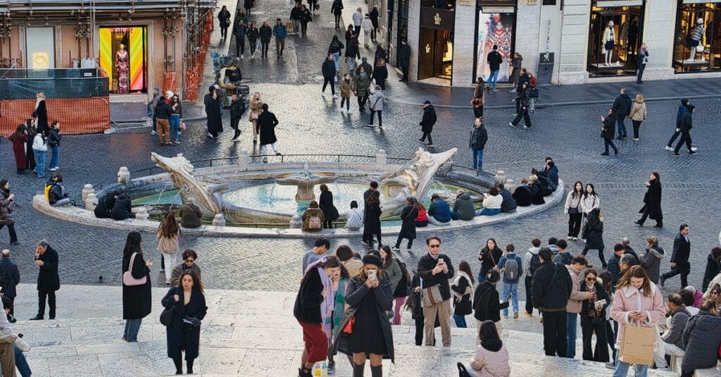 Bustling crowd at Piazza di Spagna, Rome, showcasing vibrant city life around the Barcaccia Fountain.