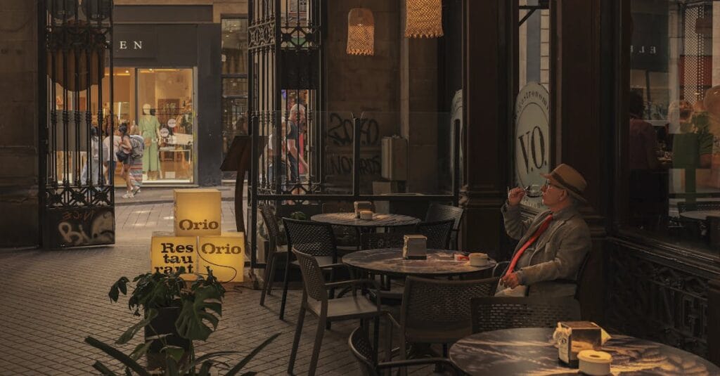 A relaxed man enjoys a drink at a cozy café in bustling Barcelona.