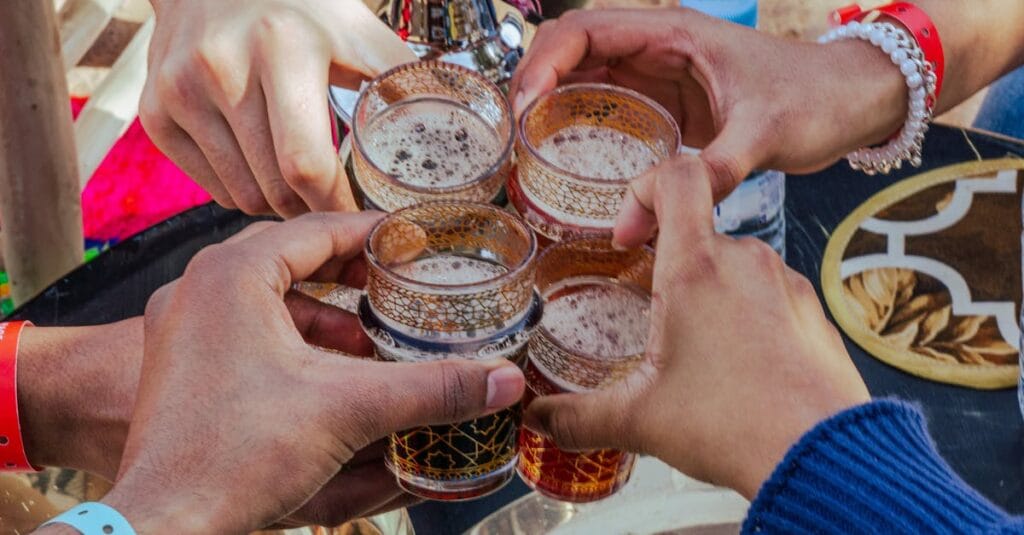 Five people toasting with Moroccan tea at an outdoor setting in Marrakesh.