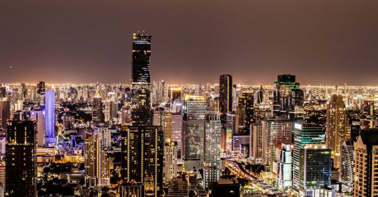 A vibrant night view of Bangkok's illuminated skyline featuring modern skyscrapers.