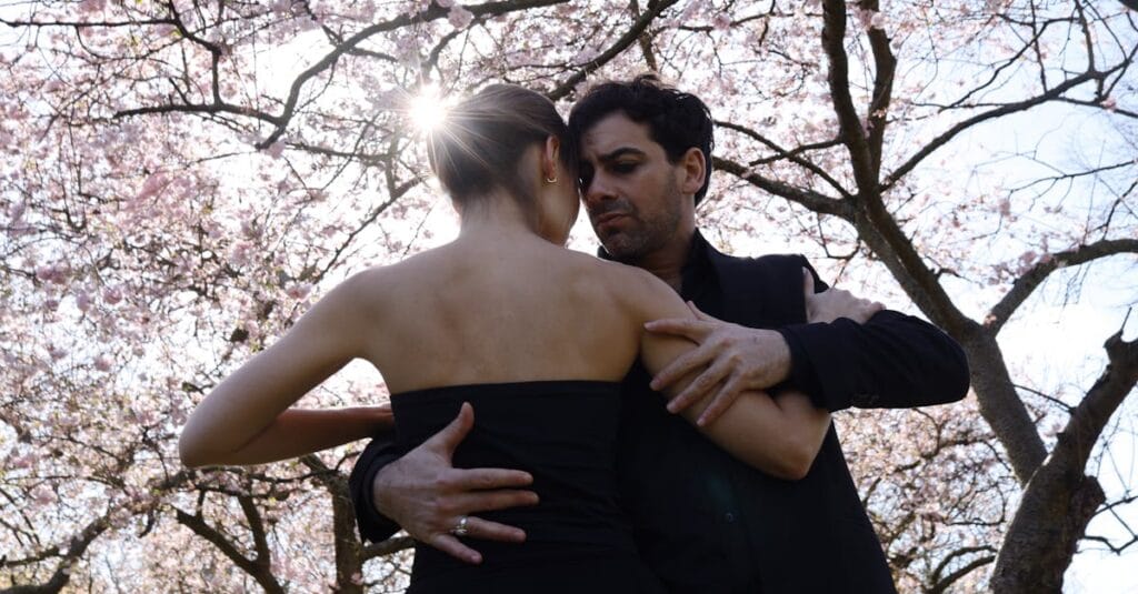 A couple dances gracefully under blooming cherry blossoms, capturing a moment of romance and tranquility.