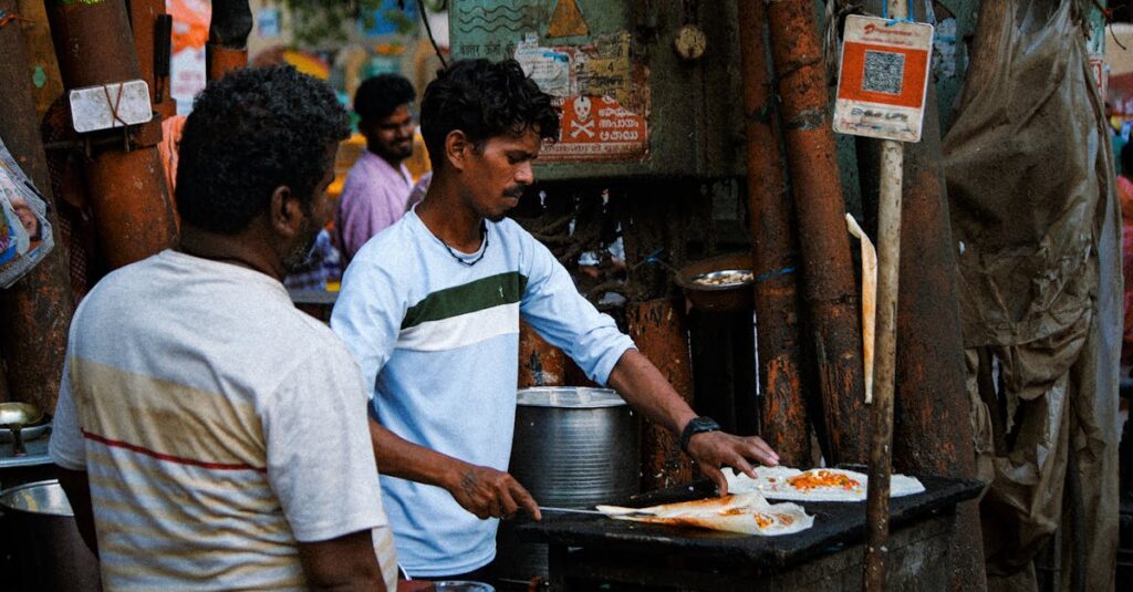 Street vendor skillfully prepares Indian dish at vibrant outdoor market. Authentic cooking scene.