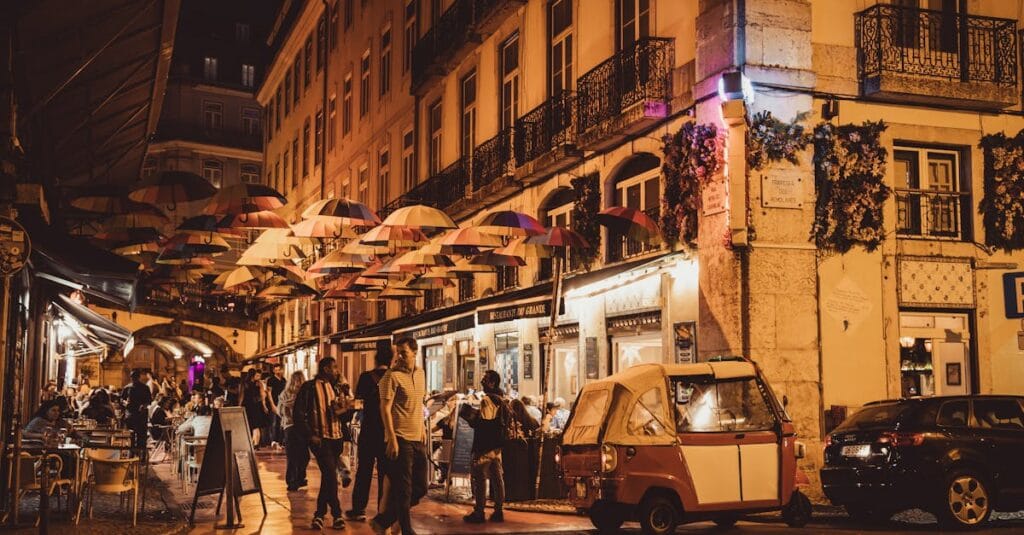 Charming street scene with umbrellas and cafes in Lisbon at night.