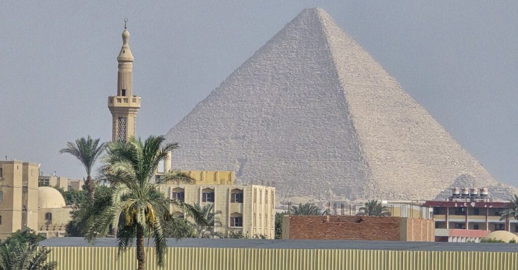 The majestic Great Pyramid of Giza with the Cairo cityscape in the foreground.