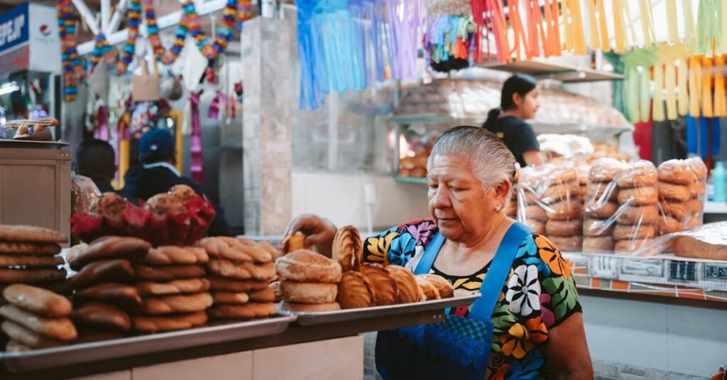 Elderly woman working in a vibrant bakery stall in Oaxaca, Mexico market.