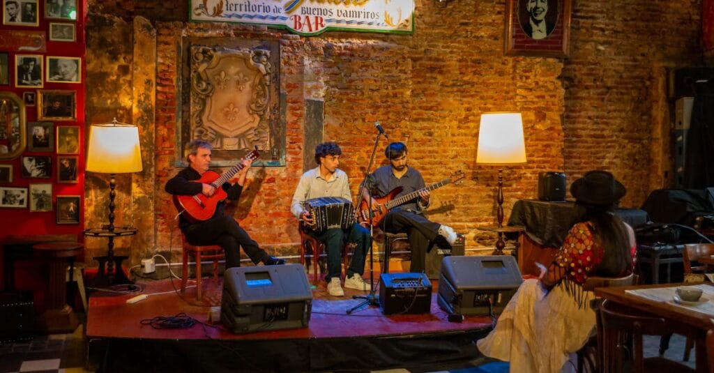 Three musicians performing live in a cozy Buenos Aires bar with guests enjoying the atmosphere.
