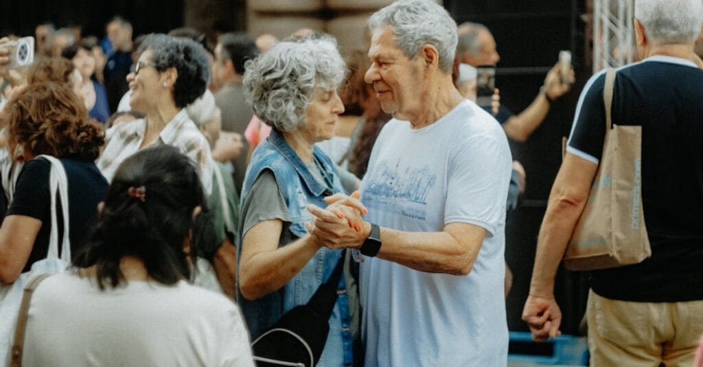 Senior couple dancing joyfully at an outdoor gathering, celebrating life and connection.