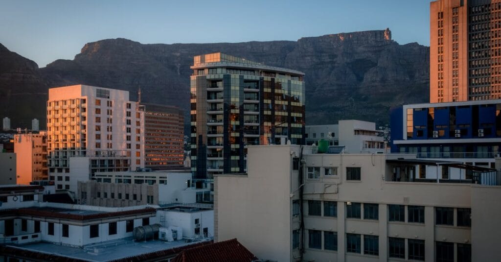 Panoramic view of Cape Town's skyline with Table Mountain at sunset, highlighting urban architecture.