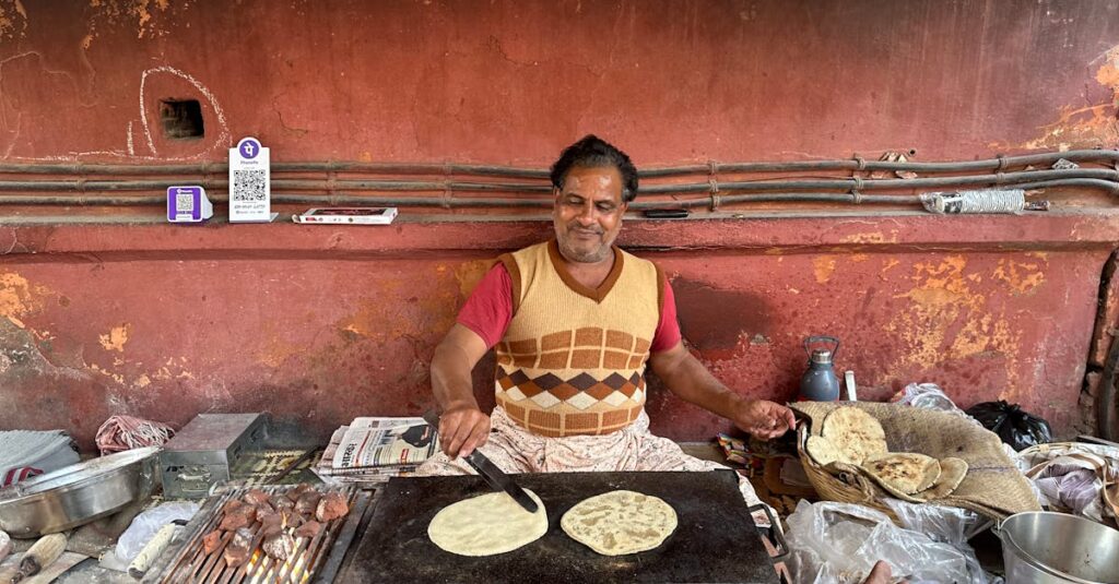 An Indian street vendor joyfully cooks traditional flatbreads on a hot griddle.