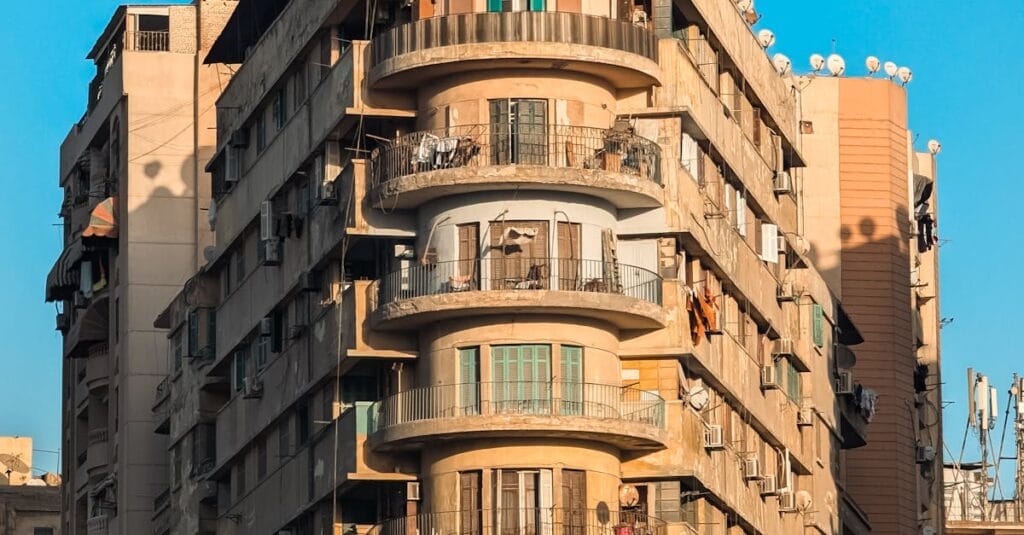 A historic apartment building in Cairo, Egypt, with distinct architectural features set against a clear blue sky.