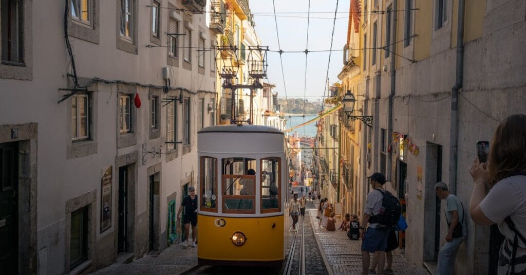 A classic yellow tram navigates a steep street in Lisbon, Portugal, capturing the city's historic charm.