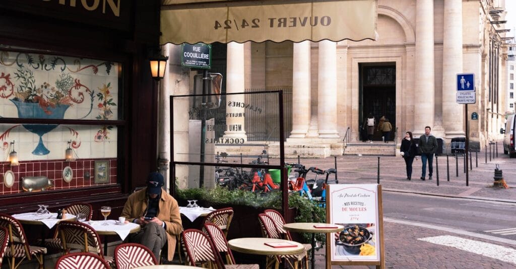 Outdoor café scene in Paris with patrons, street view, and historical architecture.