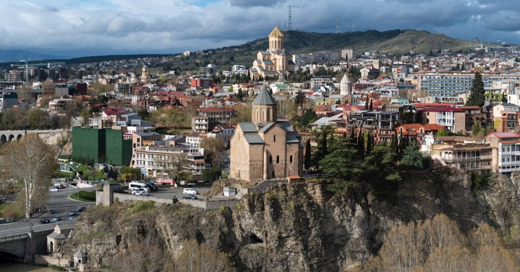 A panoramic view of Tbilisi, Georgia featuring historic churches and diverse architecture under a dramatic sky.