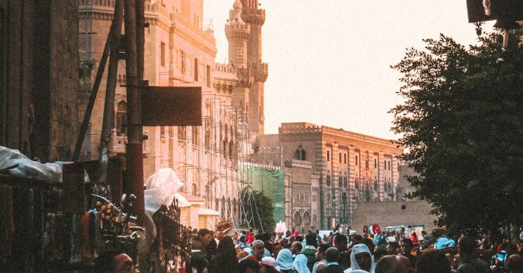 Crowd of people walking on street surrounded by walls of medieval quarter of Cairo