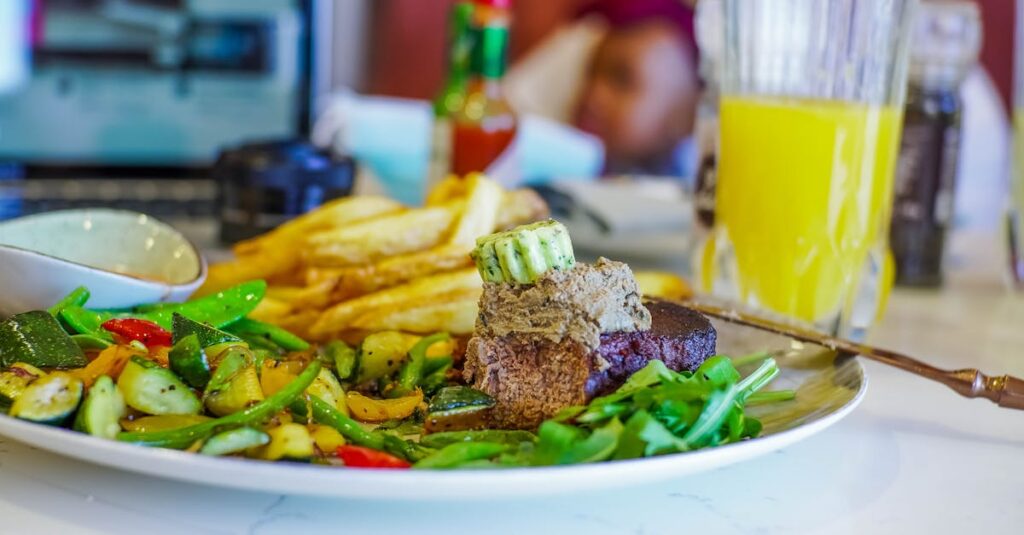 Vibrant South African dish featuring steak, vegetables, and fries served with a refreshing drink.