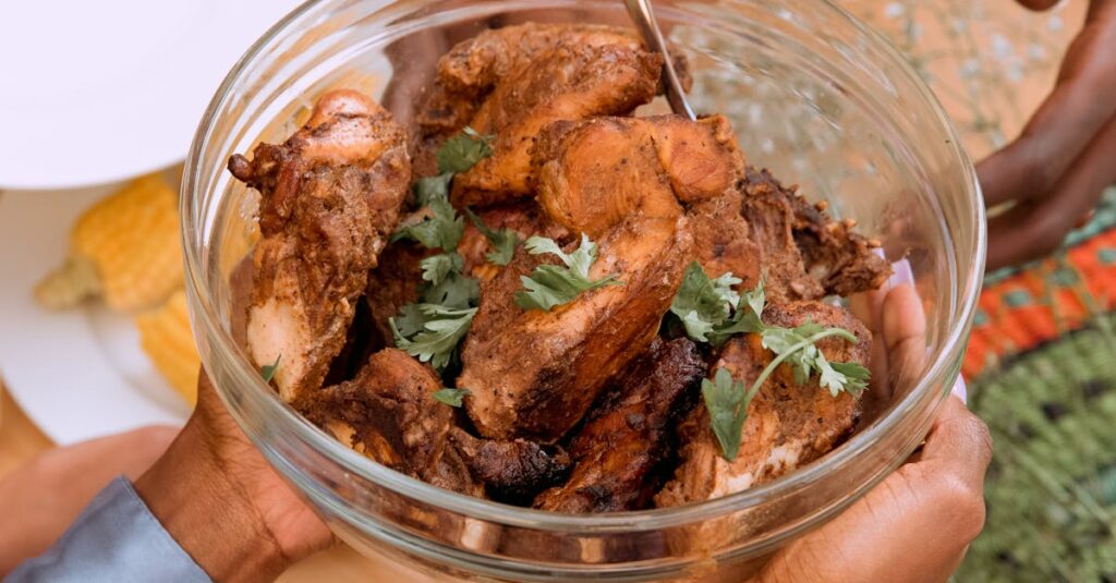 A bowl of African-style roasted meat garnished with herbs, ready to serve at a gathering.