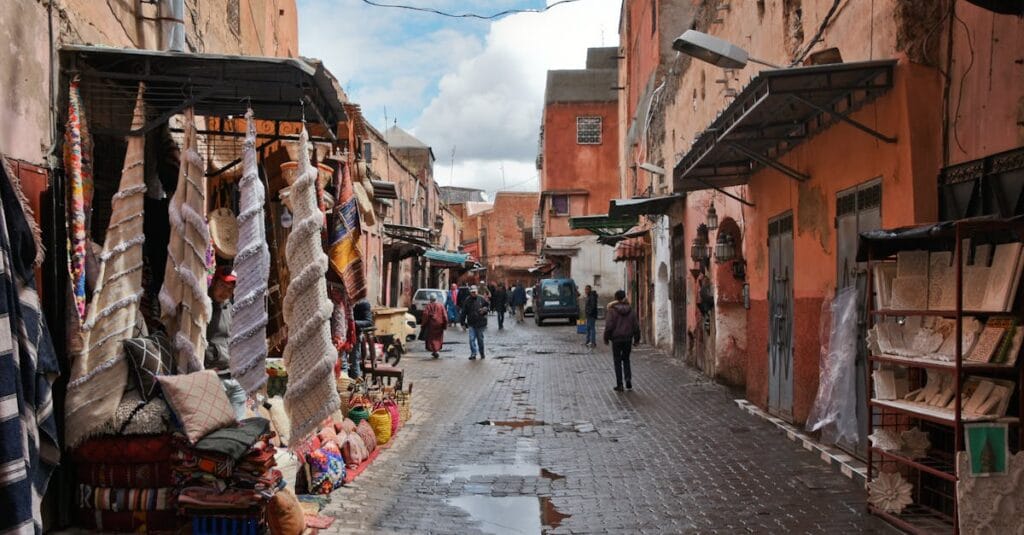 Explore the bustling streets of Marrakech with vibrant fabrics and traditional architecture in this lively market scene.