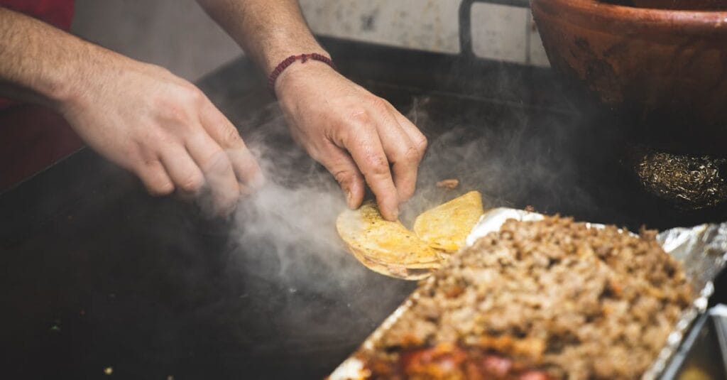 Vendor skillfully prepares authentic Mexican street tacos on a grill. Perfect for food photography.