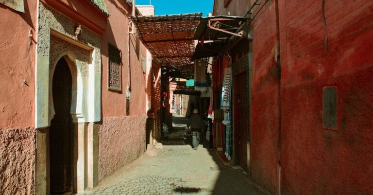 Narrow Moroccan alleyway with red buildings and a cobblestone path creating an atmospheric scene.